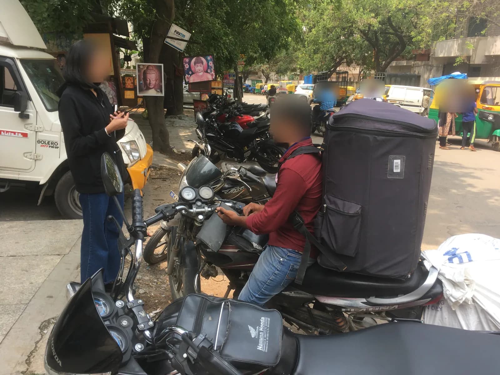 A delivery rider on a motorcycle with a large insulated bag on the back, talking to our team