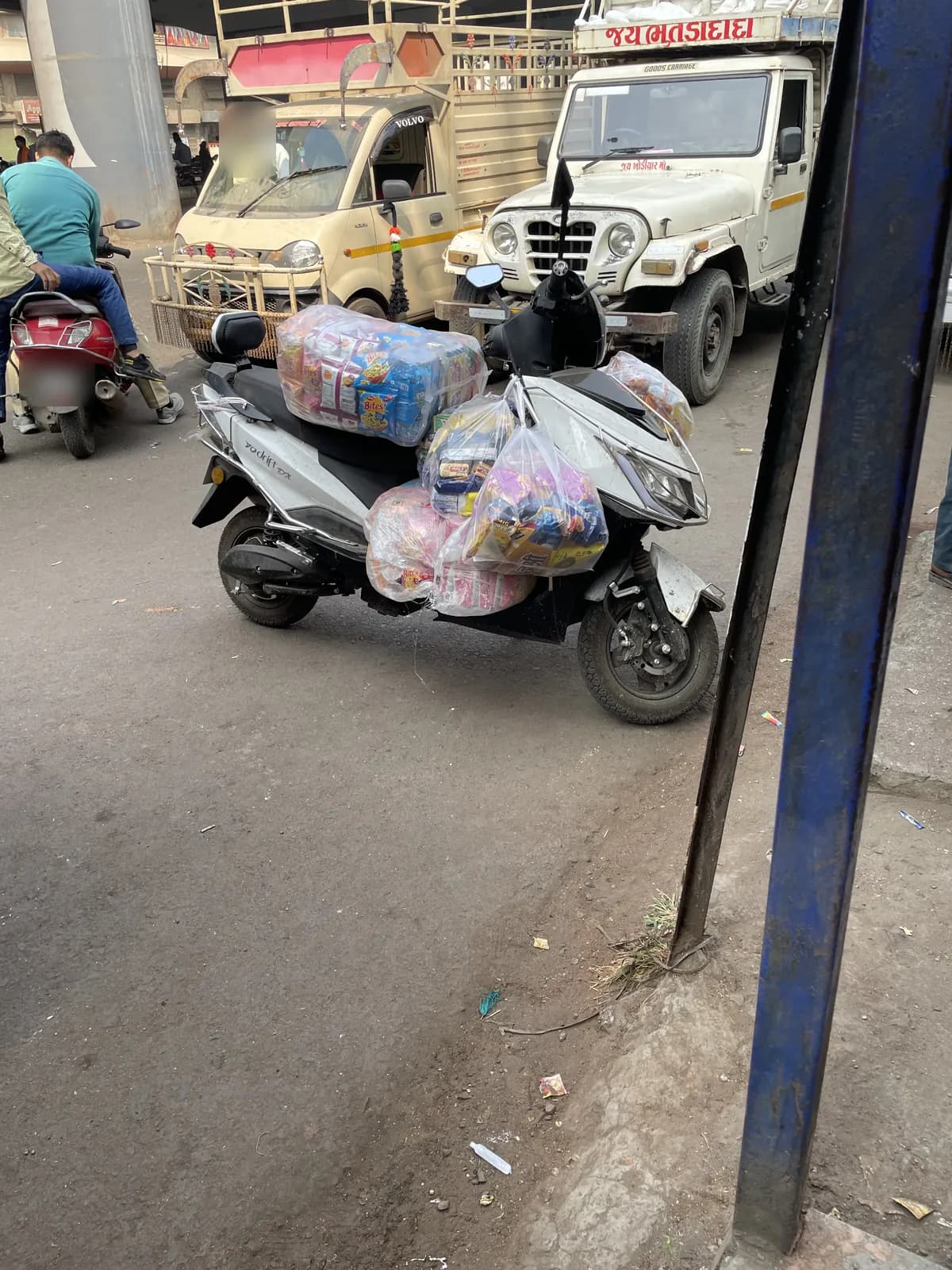 A parked scooter loaded with plastic-wrapped bundles on its footboard, seat and sides