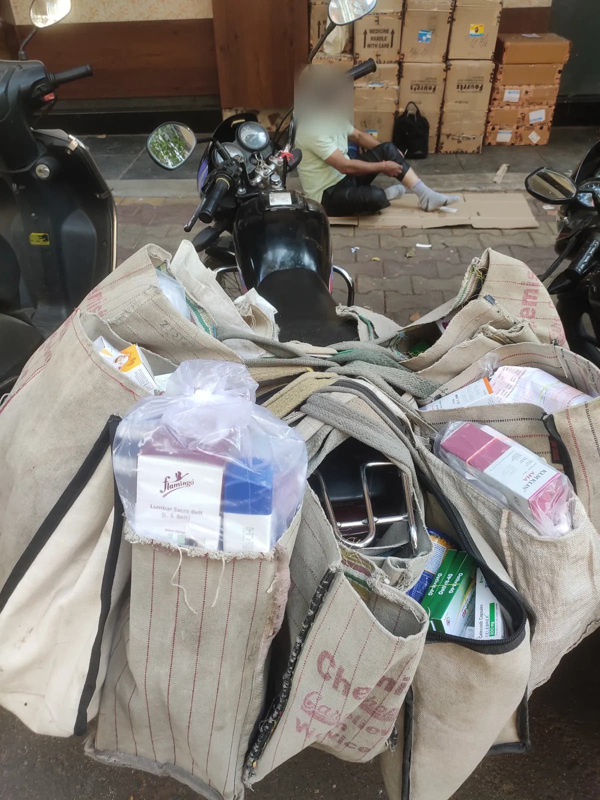 Cloth sacks of packaged goods piled on scooters outside a warehouse