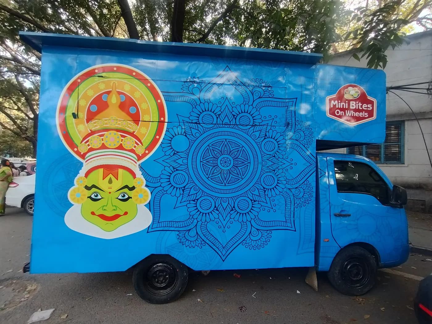 A blue painted food truck parked at the kerb on a city street
