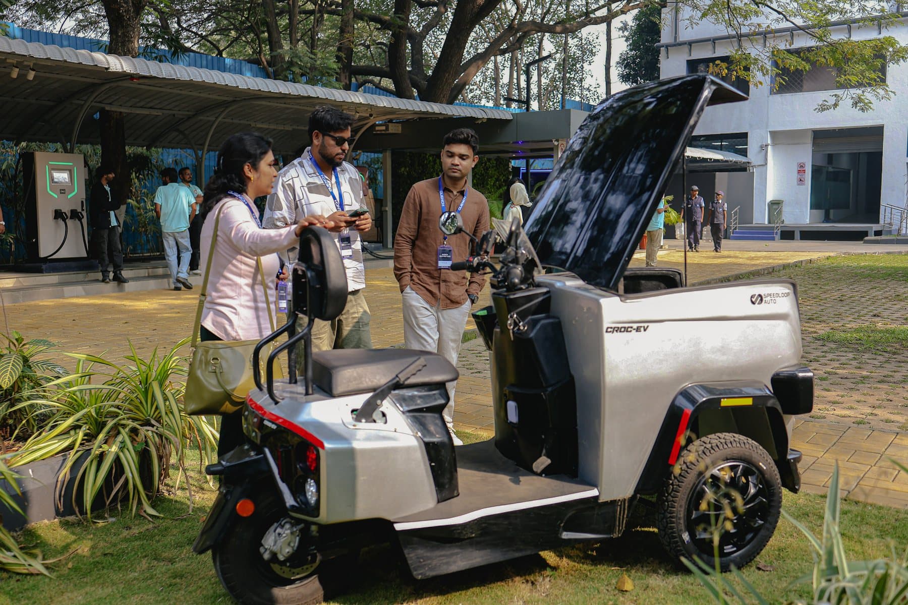 People gathered around a silver CROC EV, looking into its open cargo box