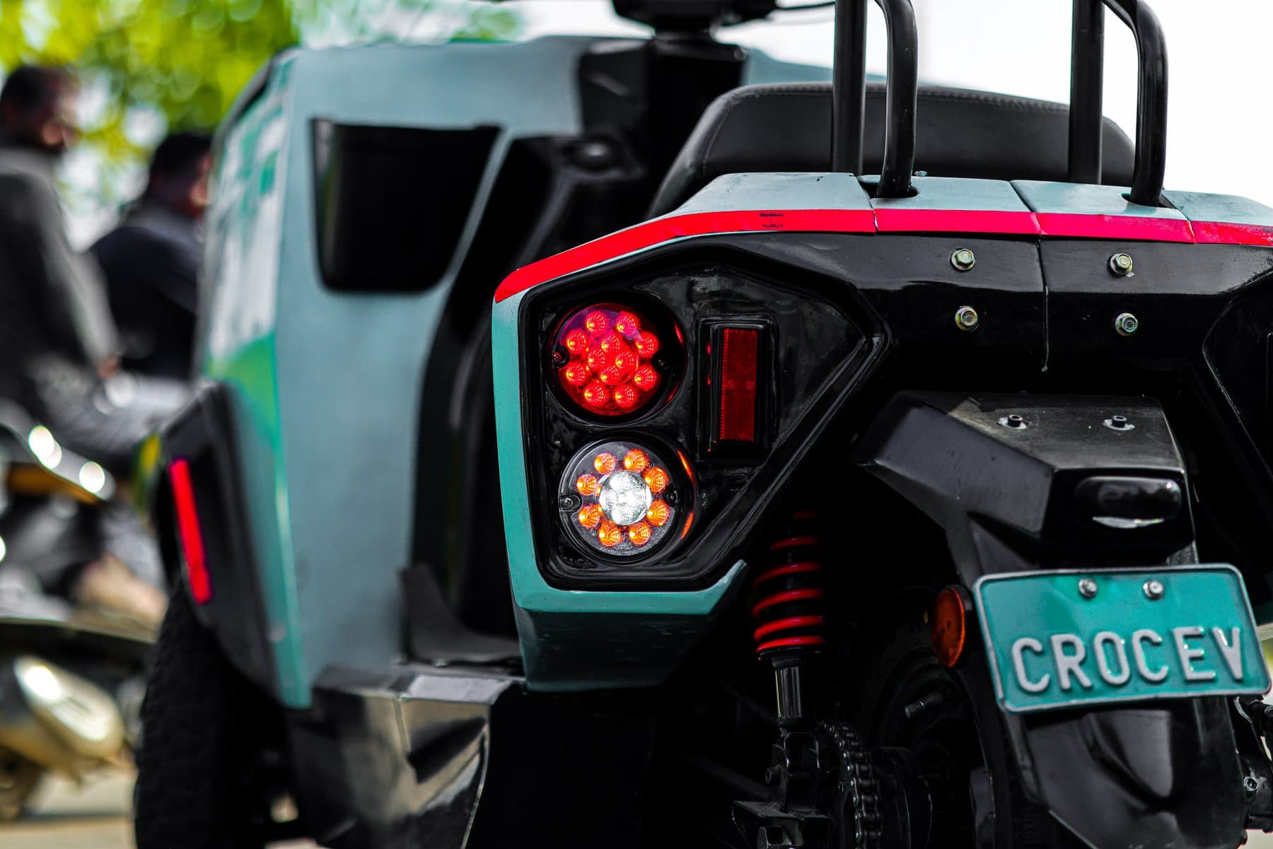 The rear lights and number plate of a teal CROC EV