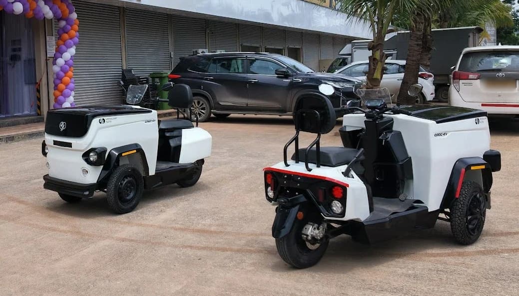 Two white CROC EVs parked outside a building